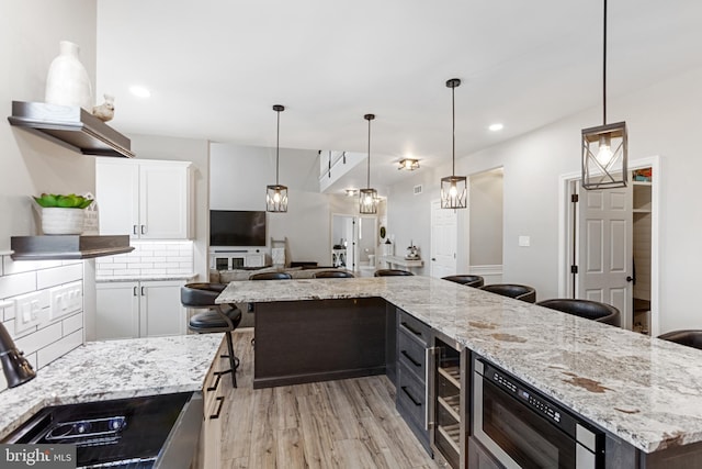 kitchen featuring open shelves, light stone counters, white cabinets, light wood finished floors, and decorative backsplash