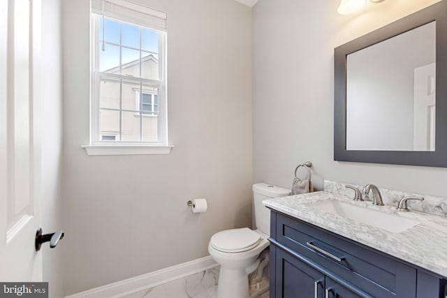 half bathroom featuring baseboards, toilet, marble finish floor, and vanity