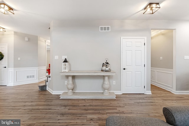 interior space featuring visible vents, a wainscoted wall, wood finished floors, and a decorative wall