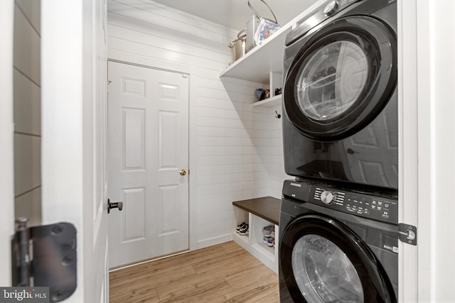 laundry area with light wood finished floors, laundry area, and stacked washer and clothes dryer