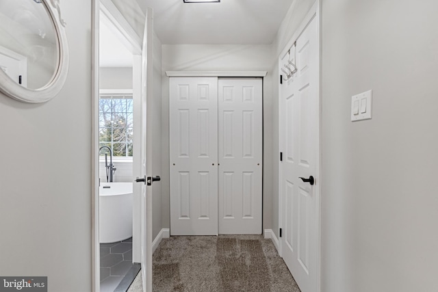 hall featuring carpet flooring and baseboards