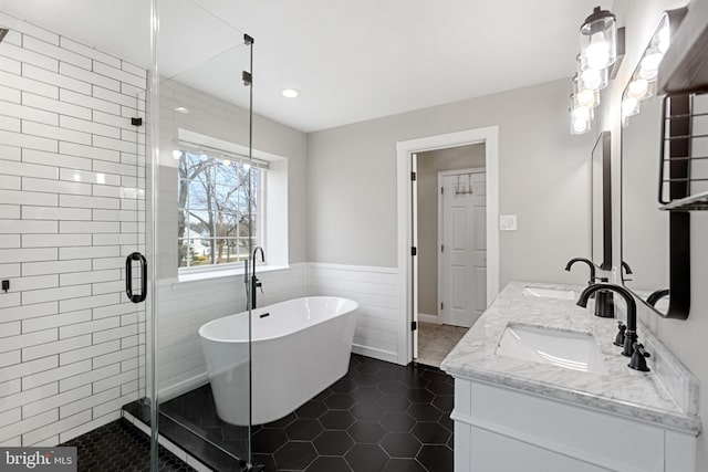 full bath with a soaking tub, double vanity, a sink, a shower stall, and tile patterned floors