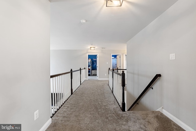 hallway with carpet, an upstairs landing, and baseboards