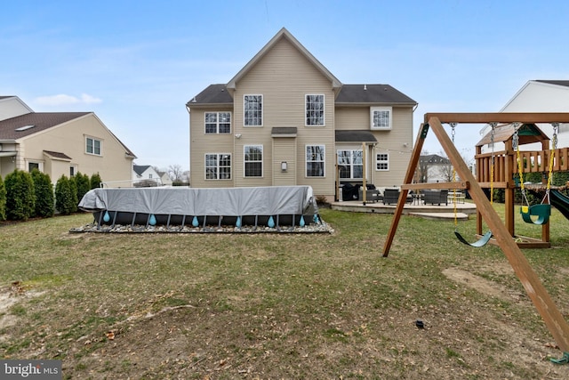 rear view of house with a fenced in pool, a lawn, and a playground