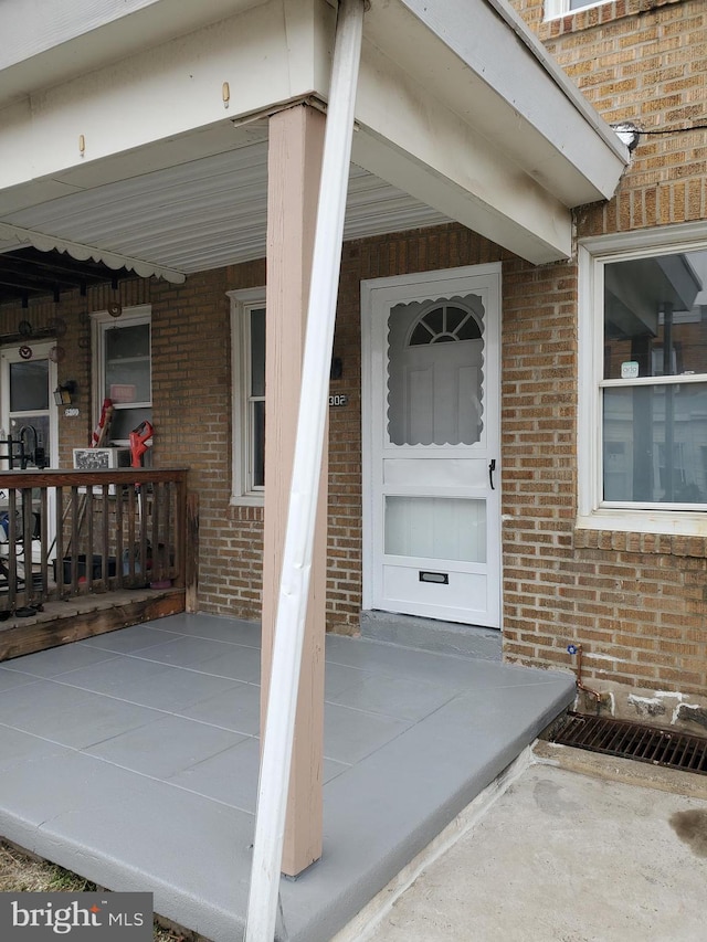 doorway to property featuring brick siding and covered porch