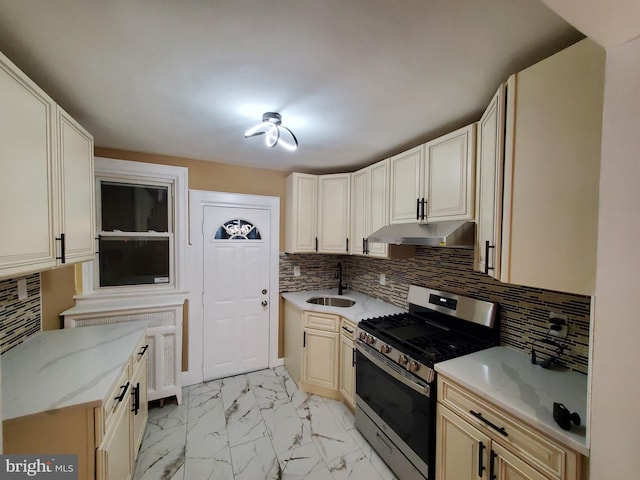 kitchen featuring stainless steel gas range oven, light stone countertops, under cabinet range hood, marble finish floor, and a sink