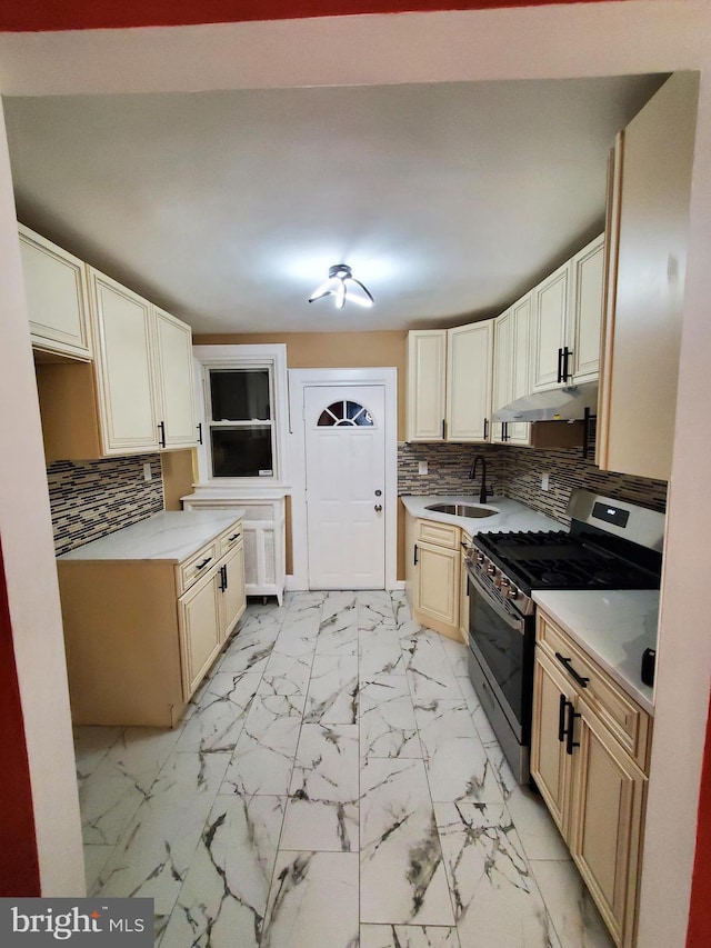 kitchen featuring stainless steel gas range, a sink, decorative backsplash, light countertops, and marble finish floor