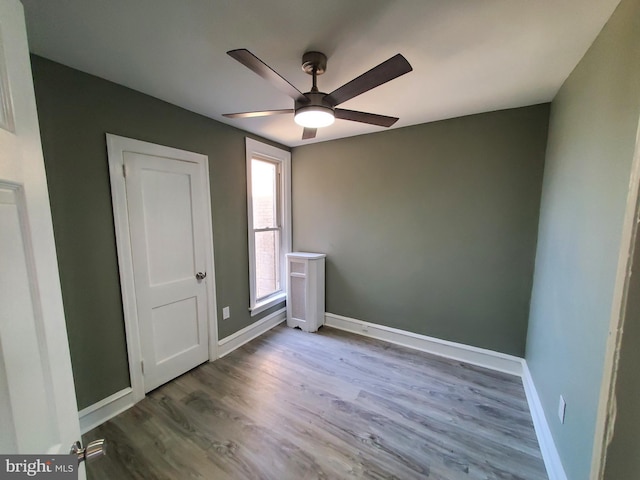 unfurnished bedroom with a ceiling fan, baseboards, and wood finished floors