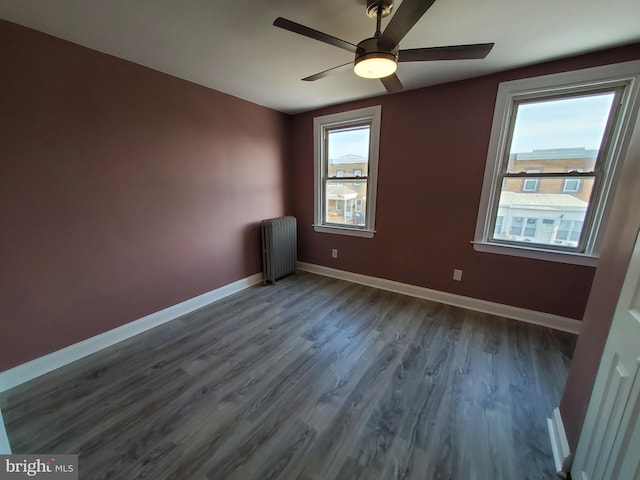 spare room featuring a ceiling fan, radiator heating unit, a healthy amount of sunlight, and baseboards