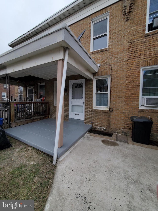 doorway to property featuring brick siding and covered porch