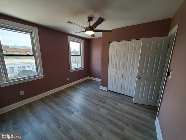 unfurnished bedroom featuring a closet, baseboards, wood finished floors, and a ceiling fan