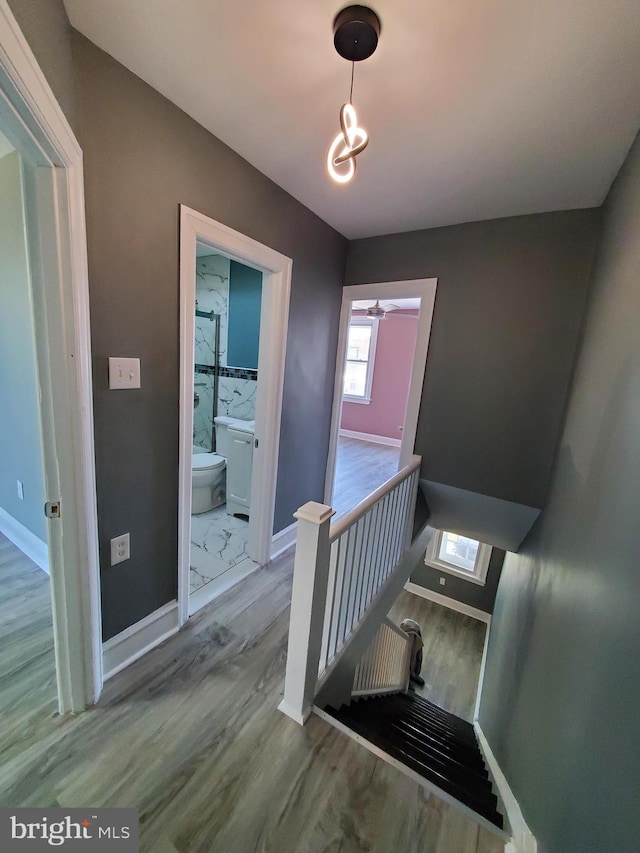 staircase featuring baseboards, wood finished floors, and a ceiling fan