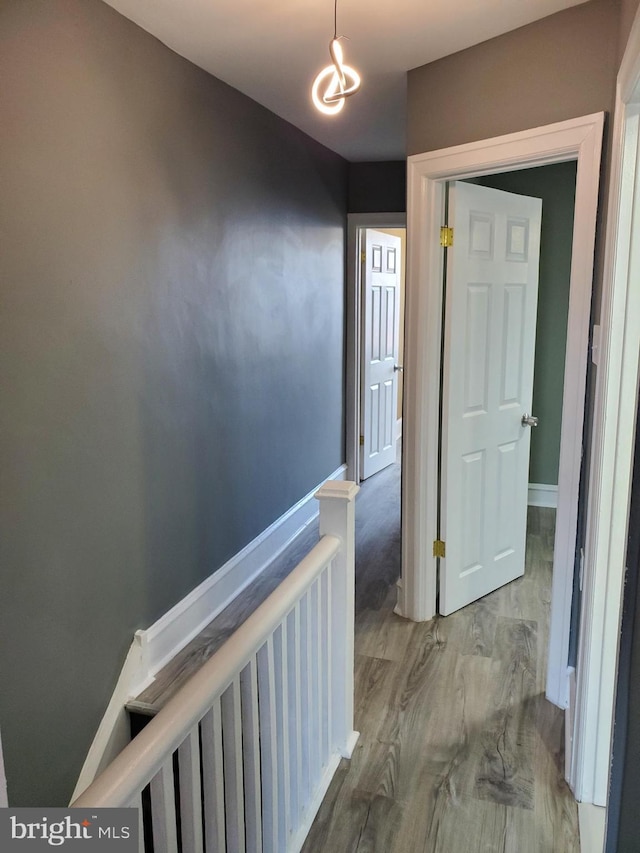 corridor featuring a notable chandelier, an upstairs landing, and baseboards