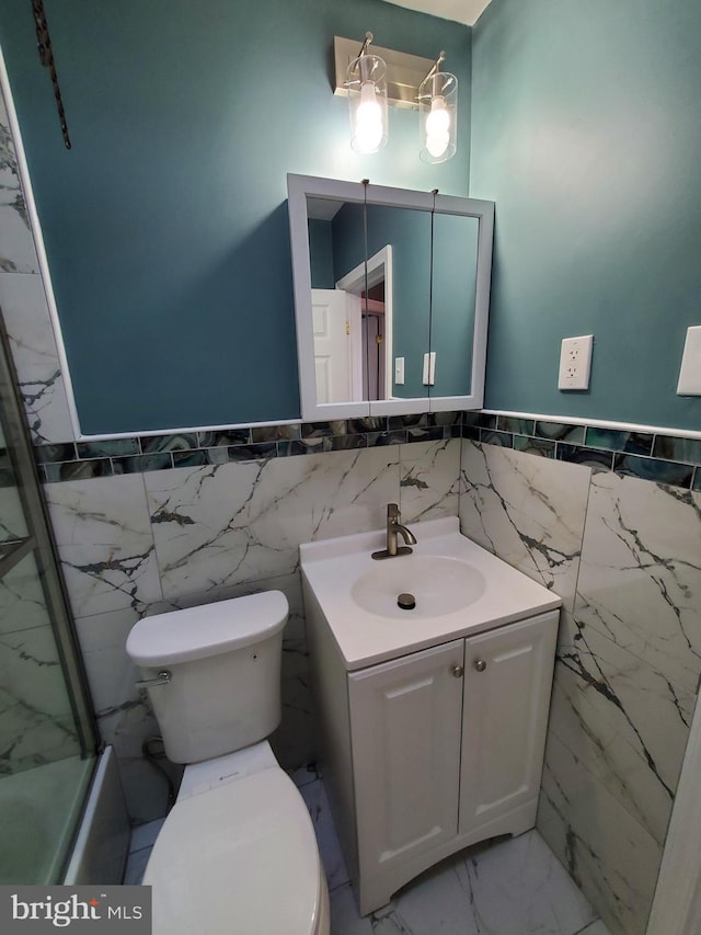 full bath featuring toilet, marble finish floor, wainscoting, and vanity