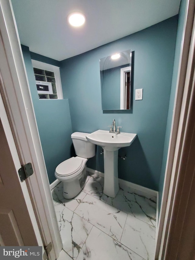 bathroom featuring a sink, baseboards, toilet, and marble finish floor