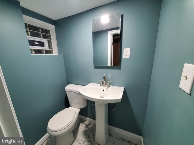 bathroom with marble finish floor, toilet, and baseboards