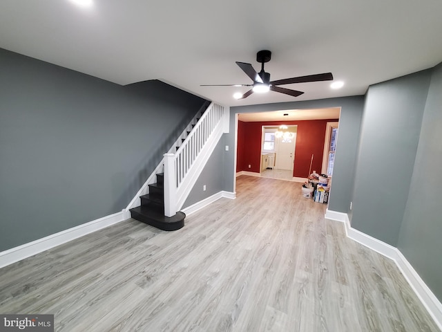 unfurnished living room featuring ceiling fan, baseboards, wood finished floors, and stairs