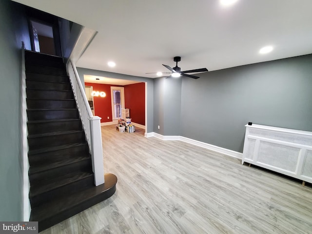 interior space with a ceiling fan, wood finished floors, stairway, radiator, and baseboards