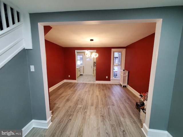 interior space with an inviting chandelier, wood finished floors, and baseboards