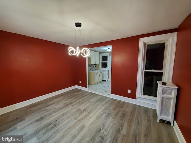 unfurnished dining area with wood finished floors and baseboards