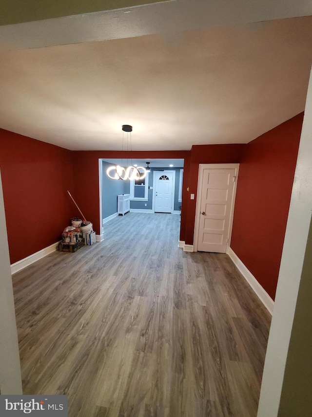 unfurnished dining area featuring an inviting chandelier, baseboards, and wood finished floors