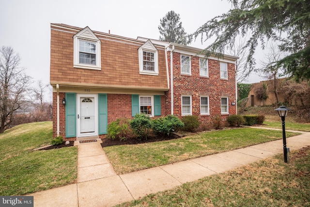 view of property featuring a front lawn and brick siding