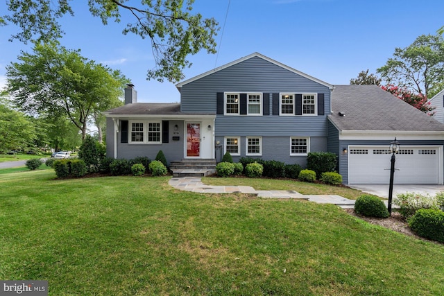 tri-level home featuring brick siding, a front lawn, a chimney, driveway, and an attached garage