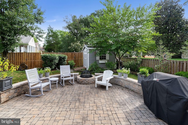 view of patio / terrace with an outbuilding, a fenced backyard, a storage unit, a fire pit, and a grill