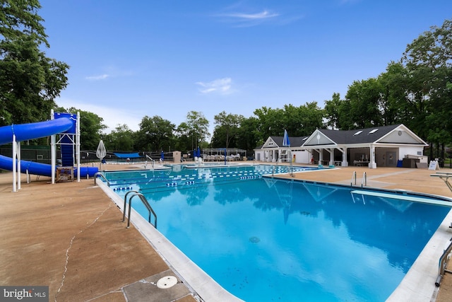 community pool with a water slide, a patio, and fence