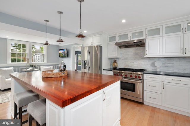 kitchen with tasteful backsplash, a kitchen island, under cabinet range hood, appliances with stainless steel finishes, and white cabinets