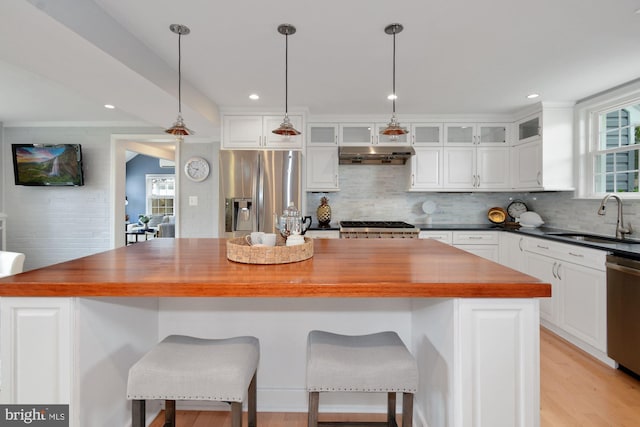 kitchen with range hood, a sink, appliances with stainless steel finishes, wood counters, and white cabinetry