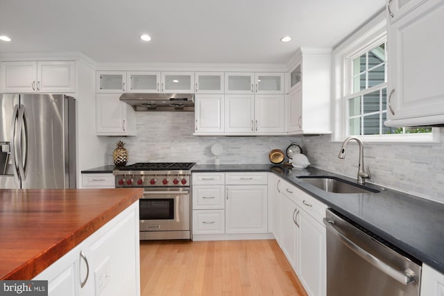 kitchen with range hood, a sink, stainless steel appliances, white cabinets, and glass insert cabinets