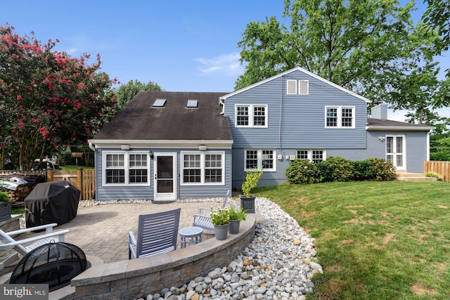 rear view of house with a fire pit, fence, a chimney, a yard, and a patio