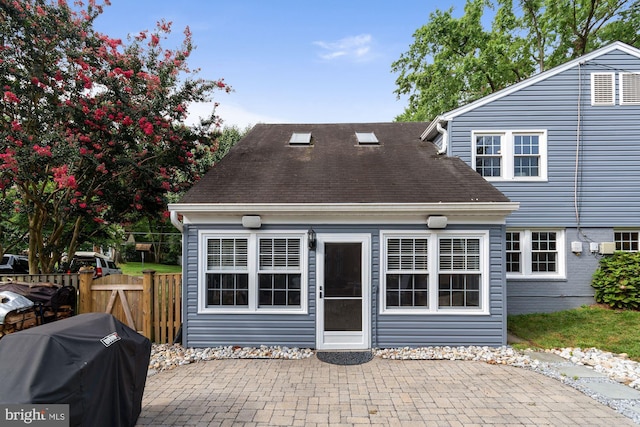 back of house featuring roof with shingles, a patio, and fence