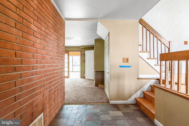 hall with stone tile flooring, visible vents, stairs, and baseboards