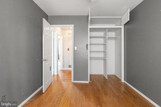 unfurnished bedroom featuring visible vents, wood finished floors, baseboards, and a closet