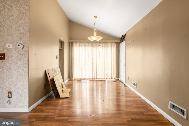 spare room with lofted ceiling, wood finished floors, visible vents, and baseboards