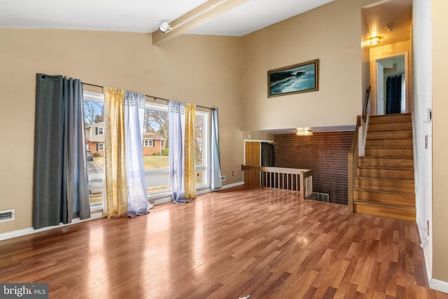 unfurnished living room featuring beam ceiling, visible vents, baseboards, and wood finished floors