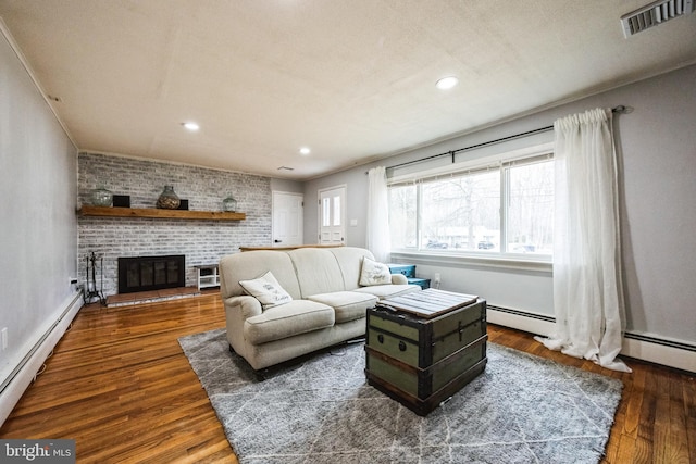 living area featuring visible vents, wood finished floors, recessed lighting, baseboard heating, and a brick fireplace