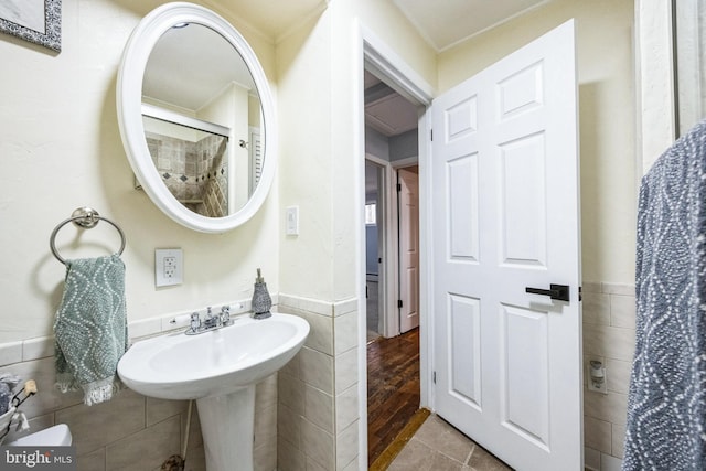 full bathroom with wainscoting, tile walls, and walk in shower