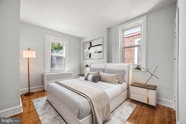 bedroom featuring radiator, baseboards, and wood finished floors