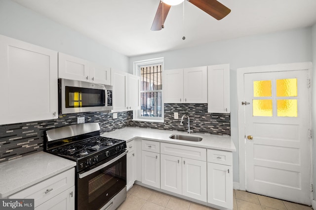 kitchen with a ceiling fan, a sink, stainless steel microwave, gas range oven, and light countertops