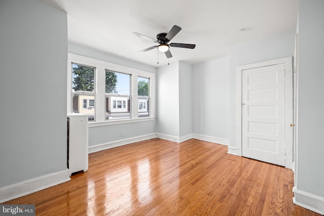 spare room with light wood finished floors, baseboards, and a ceiling fan