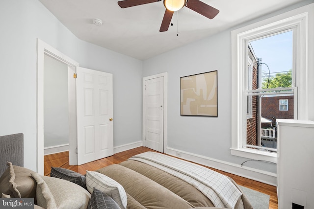 bedroom featuring baseboards, wood finished floors, and a ceiling fan