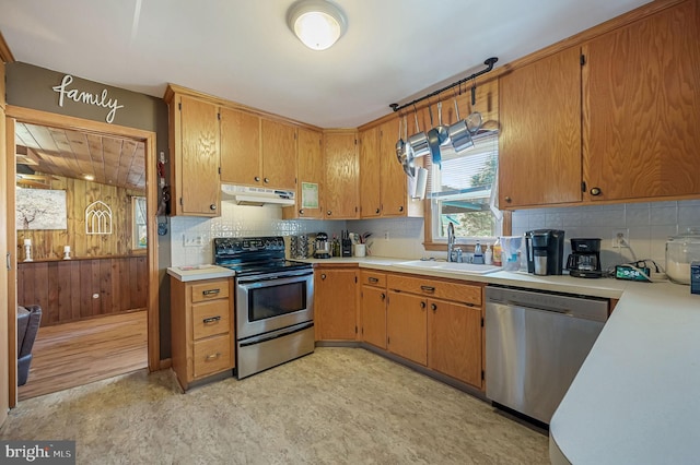 kitchen with a sink, light countertops, under cabinet range hood, and stainless steel appliances