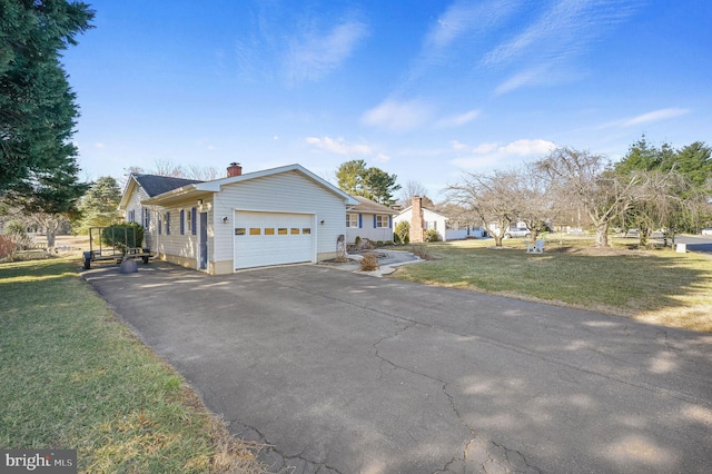 view of front of property with a front yard, a garage, driveway, and a chimney