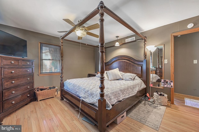 bedroom featuring ceiling fan, visible vents, baseboards, and light wood-style flooring