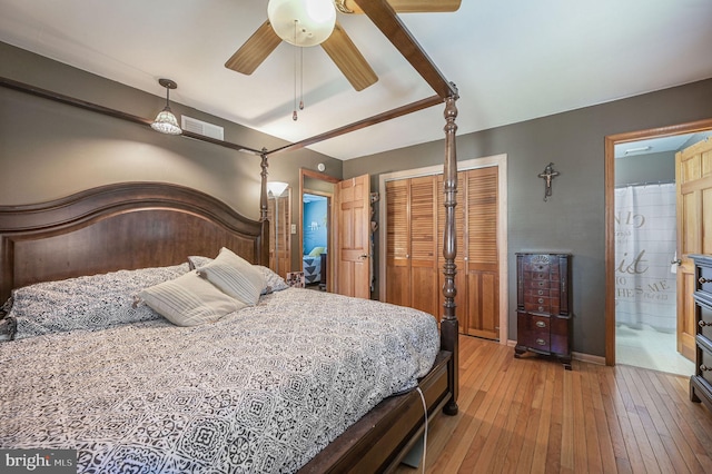 bedroom with baseboards, visible vents, ensuite bath, multiple closets, and light wood-type flooring