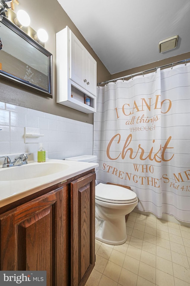 full bathroom featuring toilet, tile walls, wainscoting, tile patterned flooring, and vanity