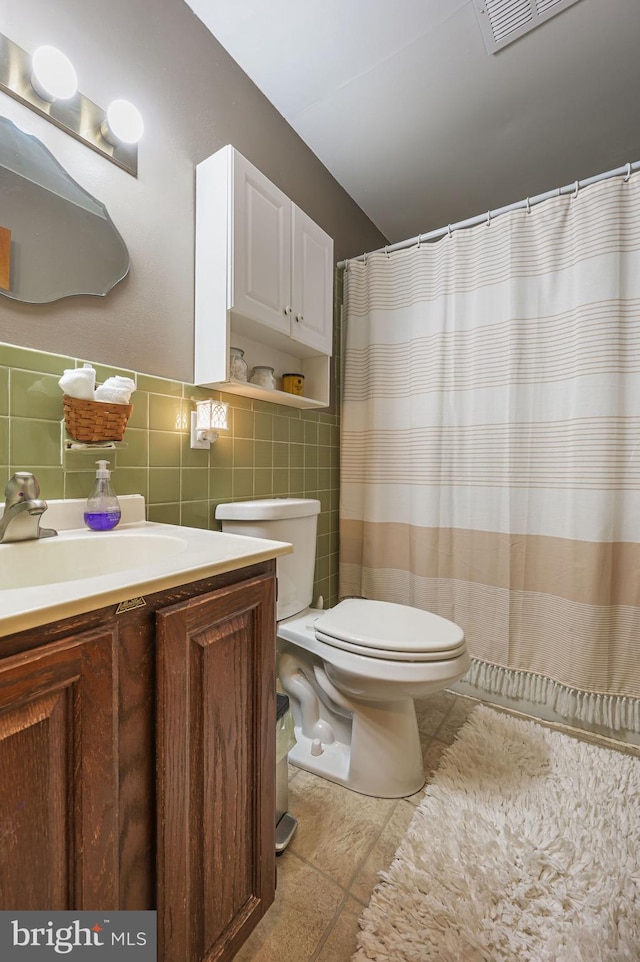 full bath featuring tile patterned flooring, visible vents, toilet, vanity, and tile walls